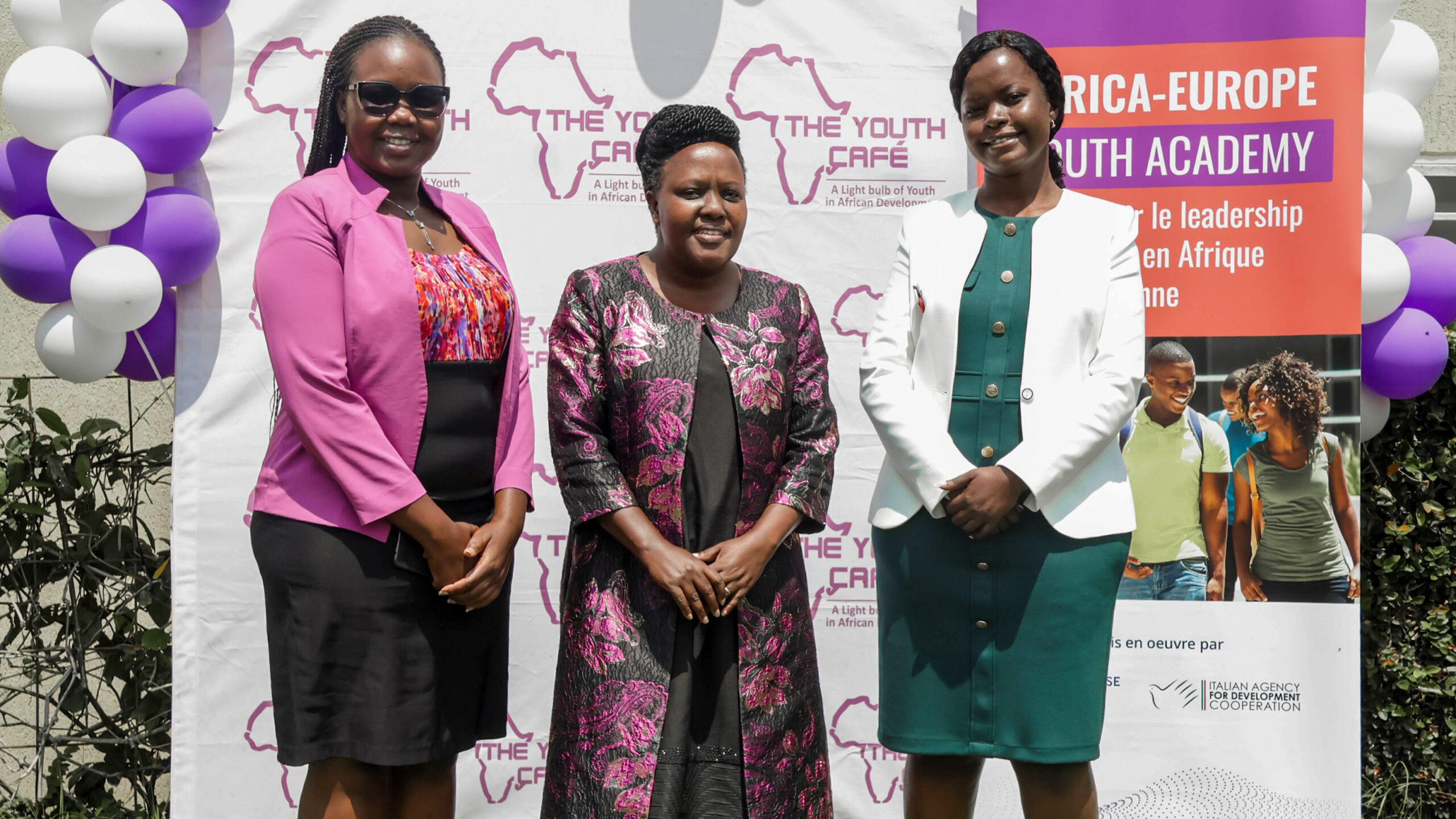 Three participants standing outdoors in front of The Youth Café and Africa-Europe Youth Academy banners during the AEYA Launch event in Nairobi.