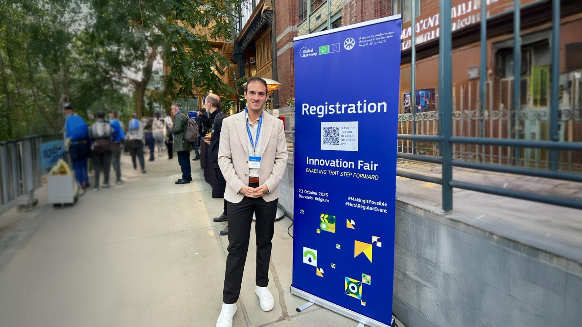 Konstantinos Maragkos from Youthmakers Hub posing in fron of Innovation Fair 2025 banner.