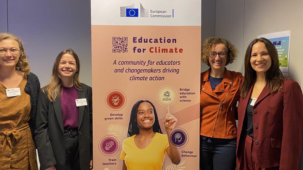 Four participants posing beside a European Commission “Education for Climate” banner promoting climate action and green skills.