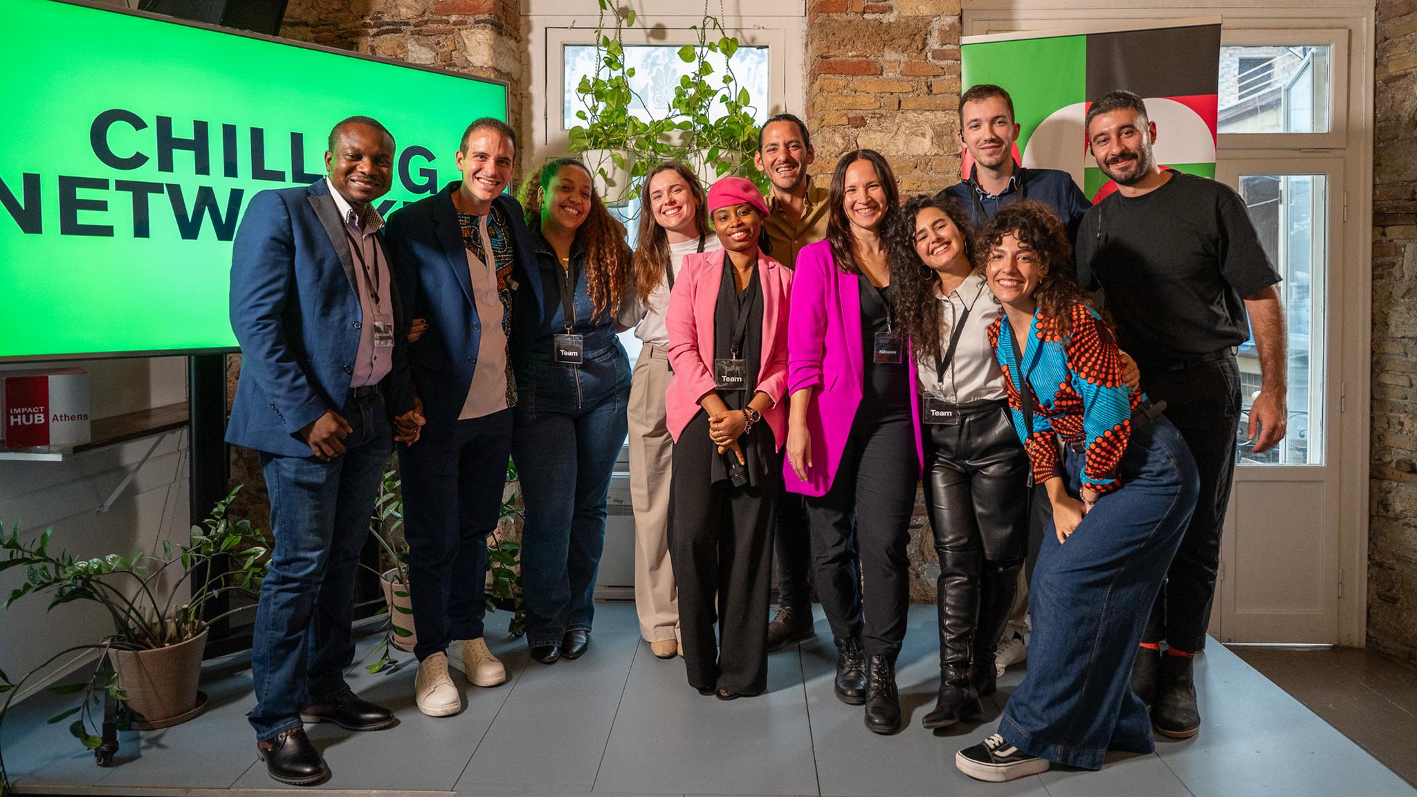 Youthmakers Hub team members posing together in front of windows and a monitor during the AGE Summit 2025.